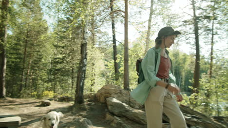 Woman-Walking-in-Woods-and-Petting-Dog-in-Travel-Trailer